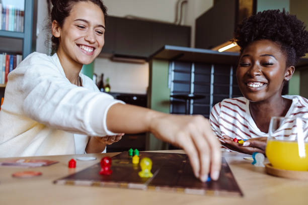 Mother and her teenage daughters playing board games at home