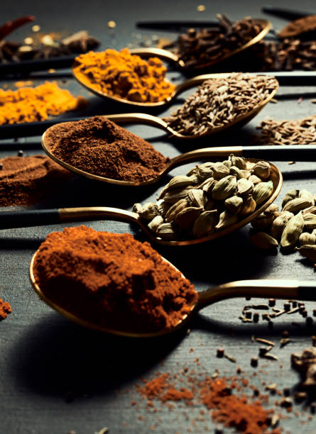 Spices, seasonings and masala used for cooking, flavoring and ingredients of spicy meals from indian cuisine. View of spoons with assorted aromatics to make a delicious curry or a whole feast especias, condimentos y hierbas utilizadas para la cocina culinaria por un chef para hacer una comida, en cucharas en la superficie de una cocina. vista de cucharas con aromáticos surtidos para hacer un delicioso curry o un festín entero