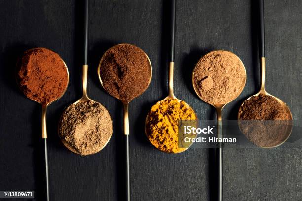 Colorful Range Of Spoons Of Herbs And Spices To Add Flavor To Food While Cooking Top View Of Seasoning For An Indian Curry Dish Recipe Isolated On A Black Background Stock Photo - Download Image Now