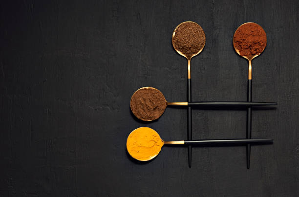 Colorful various, herbs and spices on spoons for cooking on dark table background. Flavourful natural, dry and organic condiment seasoning used to add flavor when preparing a tasty meal at home