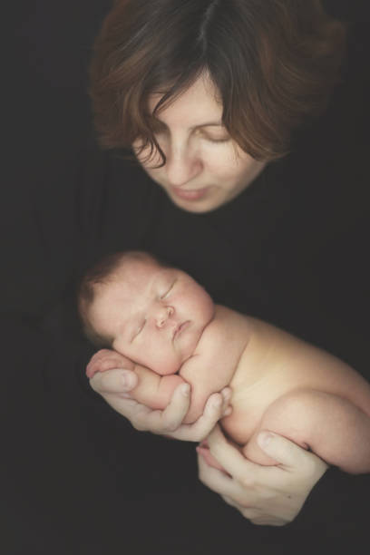 istock newborn baby mom brunette on hands, dark toning 1413812238