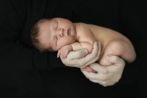 istock tender newborn baby on a dark background 1413812261