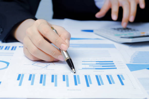 istock Businessman holding a profitability statistics analysis pen from a graph document in hand  to plan profit. 1413814386