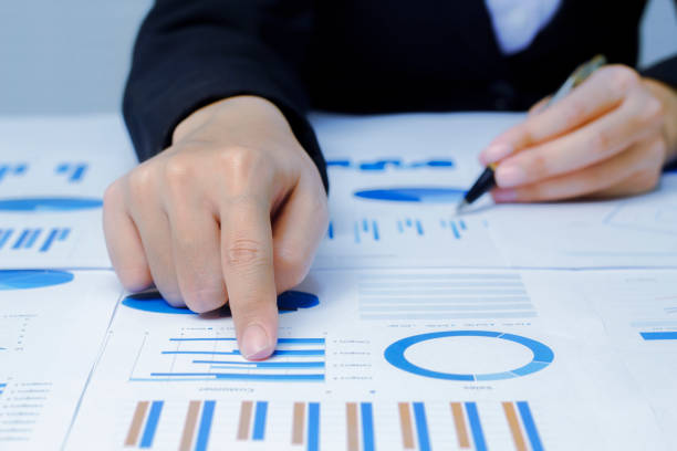 istock Businessman holding a profitability statistics analysis pen from a graph document in hand  to plan profit. 1413814391