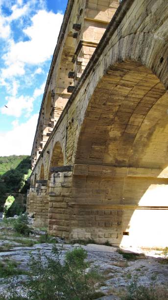 o pont du gard é uma antiga ponte romana de aqueduto construída no primeiro século d.c. e foi tombada como patrimônio mundial da unesco em 1985. (vista sob o arco na margem norte) - aqueduct roman ancient rome pont du gard - fotografias e filmes do acervo