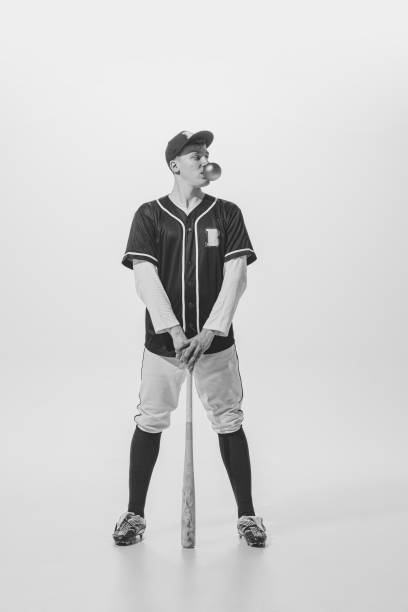 retrato de jovem, jogador de beisebol posando com chiclete e bastão. fotografia em preto e branco. esportista - men baseball baseball cap baseball bat - fotografias e filmes do acervo