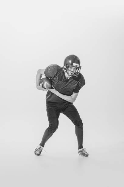 retrato de jovem, estudante universitário, jogador de futebol americano durante o jogo. fotografia em preto e branco. jogo vencedor - teamsport - fotografias e filmes do acervo