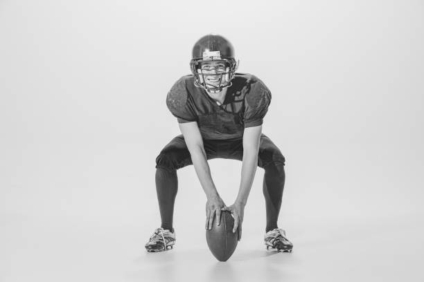 portrait of young man, american football player posing. black and white photography. cheerful, smiling sportsman - teamsport imagens e fotografias de stock
