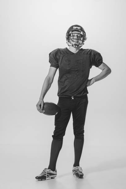 portrait of young man, american football player posing. black and white photography. smiling, laughing, winning championship - men 20s cut out 30s imagens e fotografias de stock