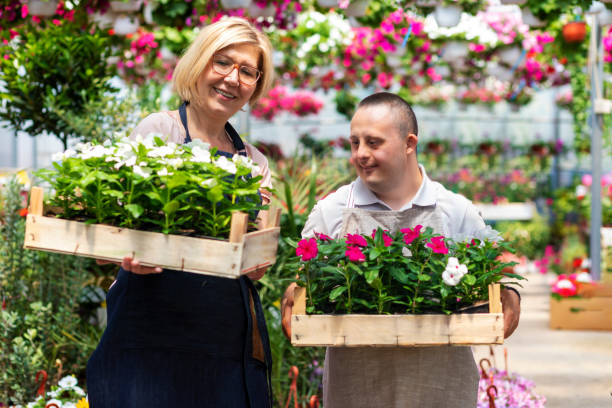 Young adult man with down syndrome working in garden center stock photo