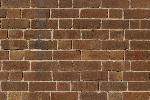 Modern red brick wall in gentle sunshine, full frame for texture use.