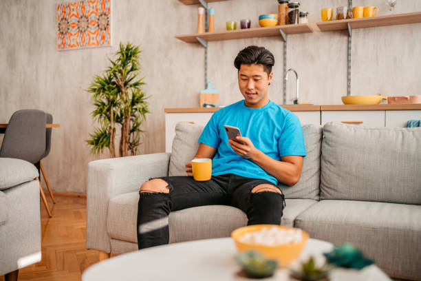 istock Young Man Relaxing At Home And Using Phone 1413821799