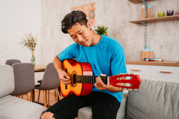 istock Young Man Playing Guitar At Home 1413821829