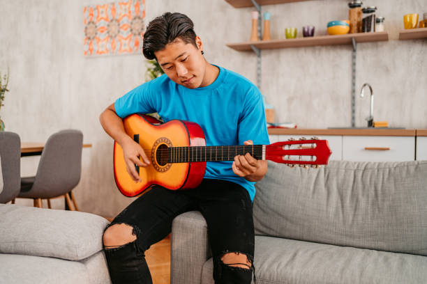 istock Young Man Playing Guitar At Home 1413821852