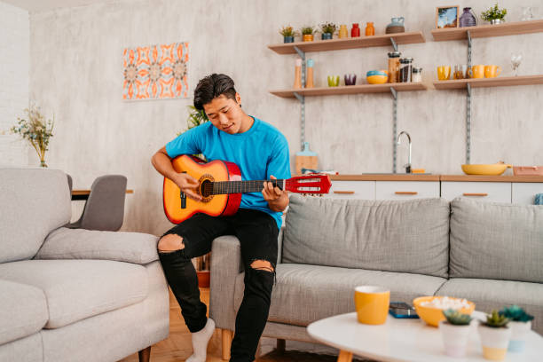 istock Young Man Playing Guitar At Home 1413821891