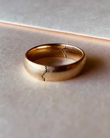 Broken golden wedding ring divorce decree theme. Divorce and separation concept.