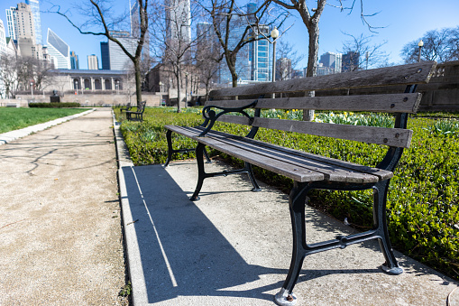 An empty wood bench at a park along Michigan Avenue in downtown Chicago during the spring with skyscrapers in the background