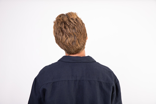 Rear view of young red-haired man wearing black shirt. Back view of man against white background. Male beauty concept