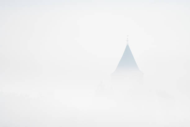 Early in the morning whit a lot of fog ,you see a roof of an church