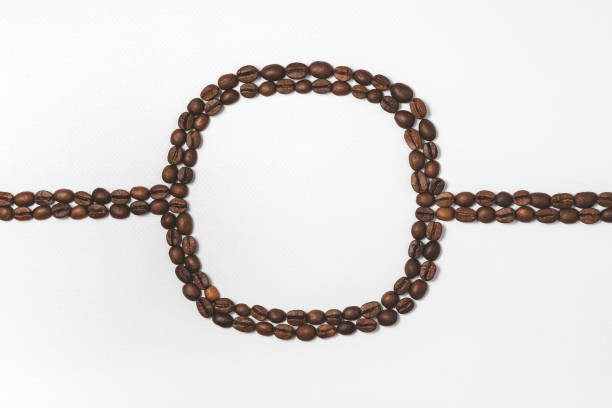 Roasted coffee beans in a row on yellow background