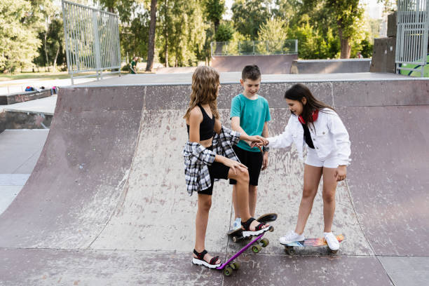 istock Kids friends with skateboards and penny boards stack their hands together and get ready for ride together on sport ramp on skate board playground. Concept of friendship sports support of children. 1413824571