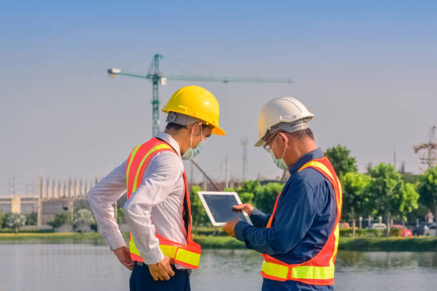 istock Asian team Construction engineers supervising progress of construction project stand on new factory, Engineering Consulting People on construction site Building inspector. 1413826248