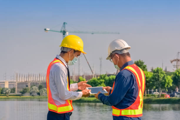 istock Asian team Construction engineers supervising progress of construction project stand on new factory, Engineering Consulting People on construction site Building inspector. 1413826255