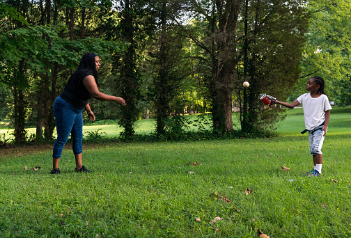 Mother and six year old son play catch with a baseball outdoors on a summer day, Midwest, Indiana, USA