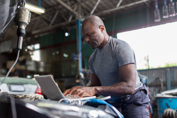 istock Mechanic using compute for Diagnostic  machine tools ready to be used with car. Car mechanic using a computer laptop to diagnosing and check up on car engines parts for fixing and repair 1413826812
