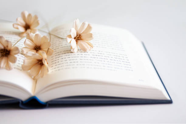 Cute vase with white daisies and an empty orange handmade paper as a mockup for your Easter, spring or summer text message on a small rustic table. Creative color editing. Very soft and selective focus. Part of a series.