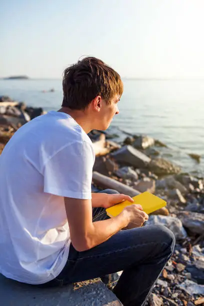 Pensive Young Man with a Book at the Seaside