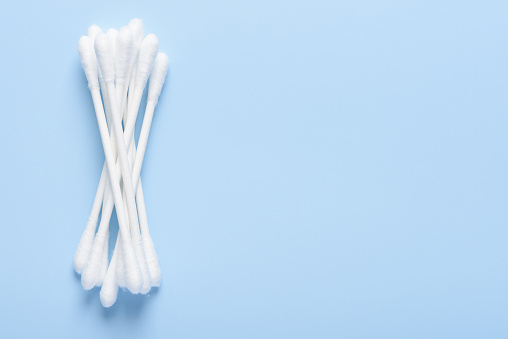 White new clean cotton swabs buds on blue background top view flay lay with side copy-space