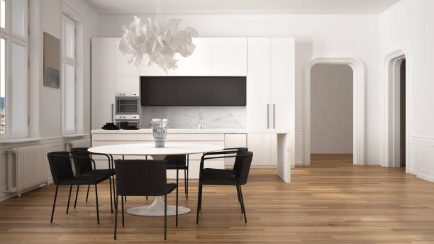 Minimalist white and black kitchen in classic room with moldings, parquet floor, dining table with chairs, marble island and panoramic windows. Modern architecture interior design