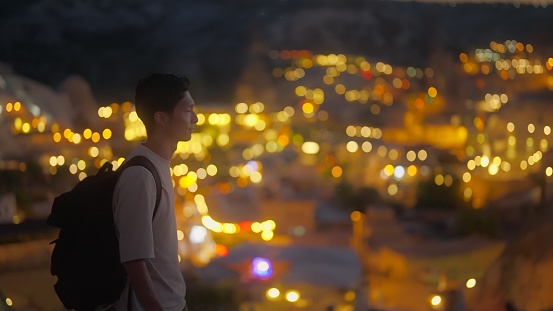 A young male tourist is walking in historical town at night.