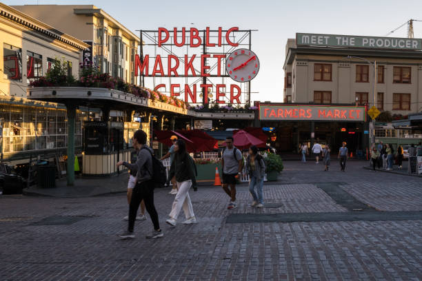 Pike Place Seattle, USA - Aug 3, 2022: The famous illuminated Pike Place Market sign illuminated late in the day as tourist pass. pike place market stock pictures, royalty-free photos & images