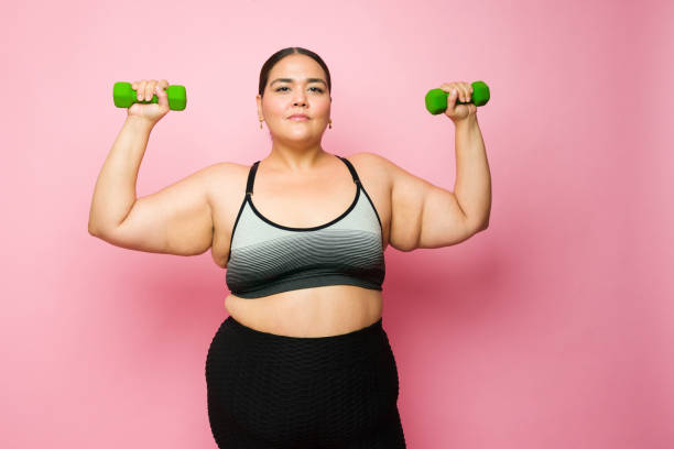 istock Determined fat woman lifting weights and losing weight with exercise 1413838242