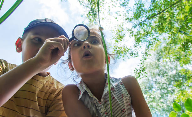 Brother And Sister Looking At Snail Through Magnifying Glass