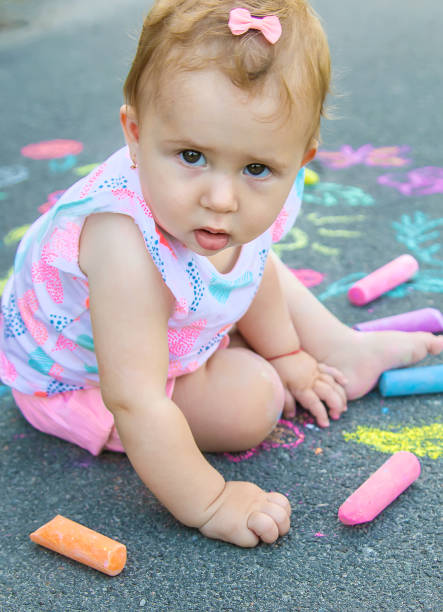 istock Cute Baby With Chalk Sitting On Sidewalk 1413839109