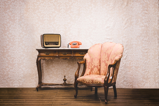 Old telephone, radio and armchair in an interior place with retro style decoration. Old retro style concept.