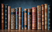istock Old books on wooden shelf. Tiled Bookshelf background.  Concept on the theme of history, nostalgia, old age. Retro style. The book is a symbol of knowledge. 1413840933