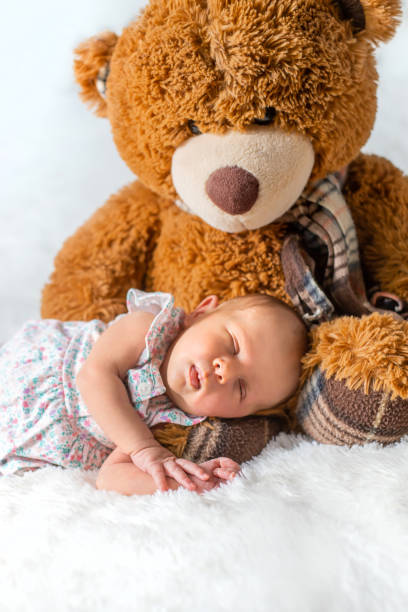 istock Cute Baby With Teddy Bear Sleeping On Bed At Home 1413841005