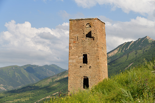Ruins and towers of the abandoned village of Goor, Dagestan, Russia. Stone towers on the background of blue sky on the emerald hills