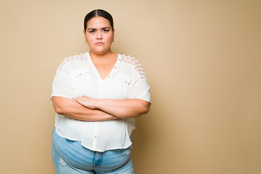 Angry hispanic young woman looking upset and annoyed after arguing or having a fight against a yellow background with copy space
