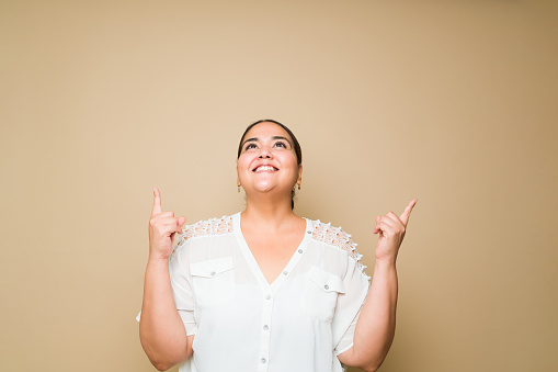 Studio portrait of a smart obese woman smiling having a great idea while thinking and using her imagination