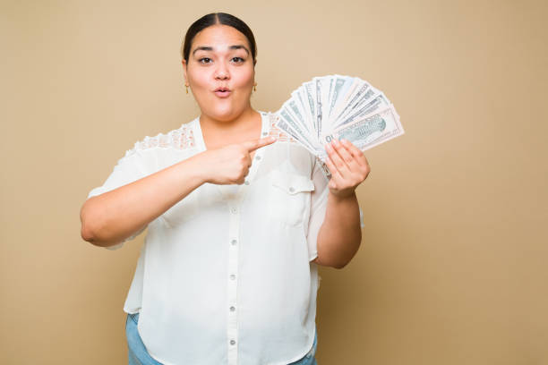 Surprised plus size woman earning a lot of money stock photo