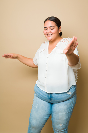 Cheerful plus size woman laughing promoting body positivity dancing with music and having fun in full length