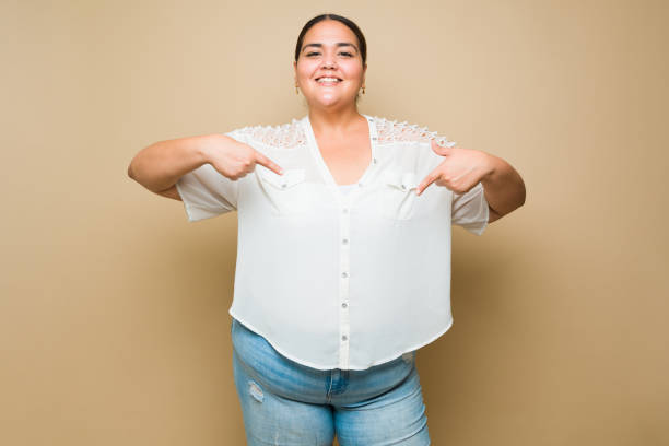 istock Cheerful beautiful fat woman pointing to copy space 1413845788