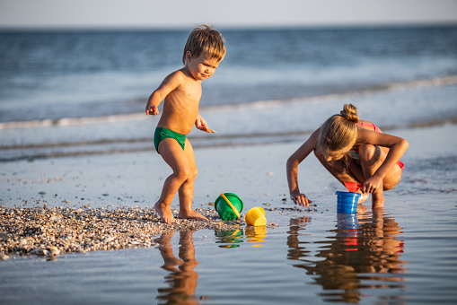 Little boys and girl applying sun protection lotion on the beach