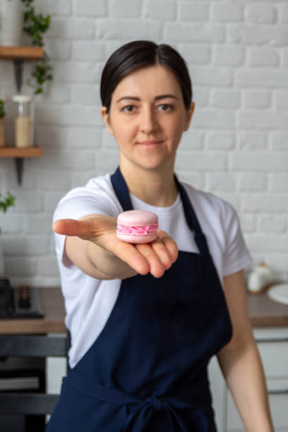 There is pink macaroon in palm of your hand. Selective focus. Image for website about desserts, food, and confectionery. stock photo