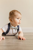istock 7-Month-Old Baby Boy Dressed Like a Little Gentleman With a Bowtie Laying on a Wooden Floor 1413848948